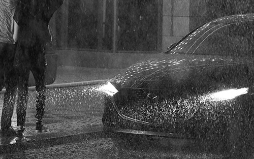 Mazda3 Sedan in the rain as a couple run towards it