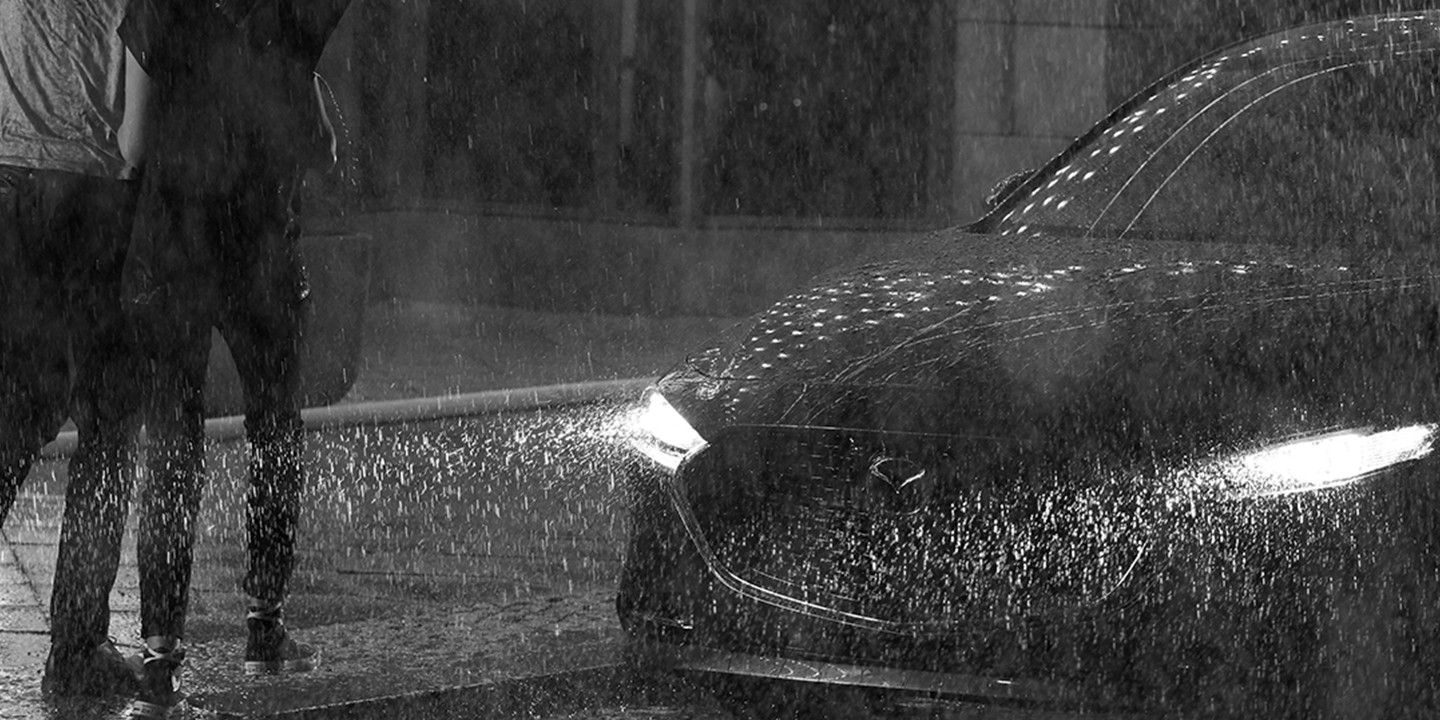 Two people walking in the rain to a Mazda3 Sedan