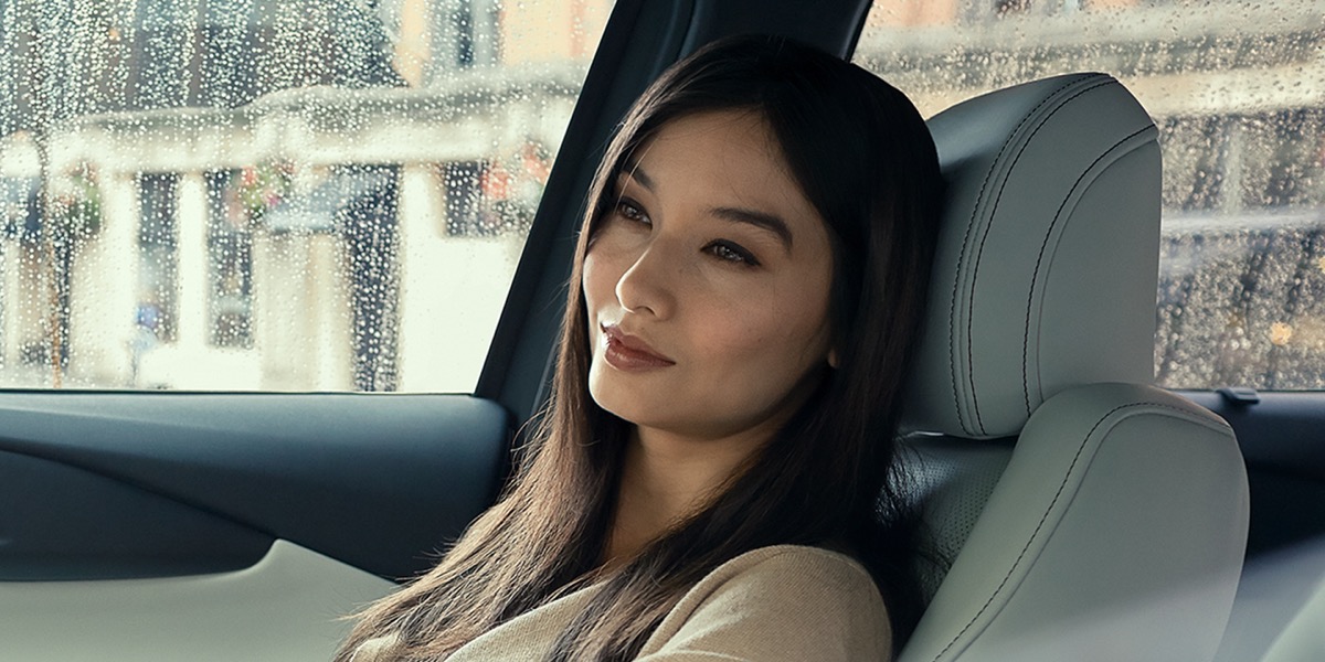 A woman in the passenger seat of a Mazda CX-9 on a rainy day