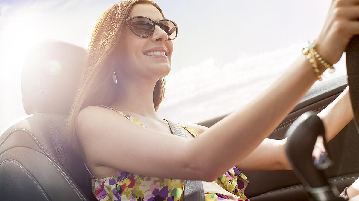 Smiling woman driving a Buick Cascada convertible.
