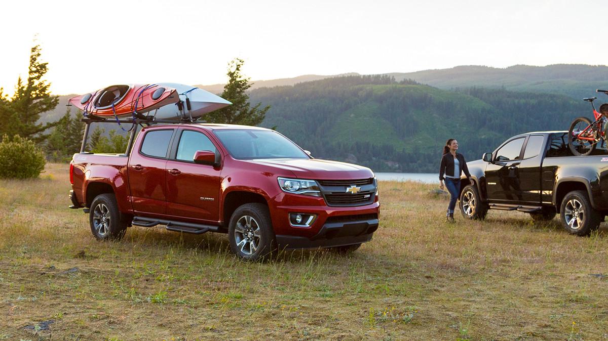 Kayak enthusiasts setting up with their Chevy Colorado trucks by a lake.