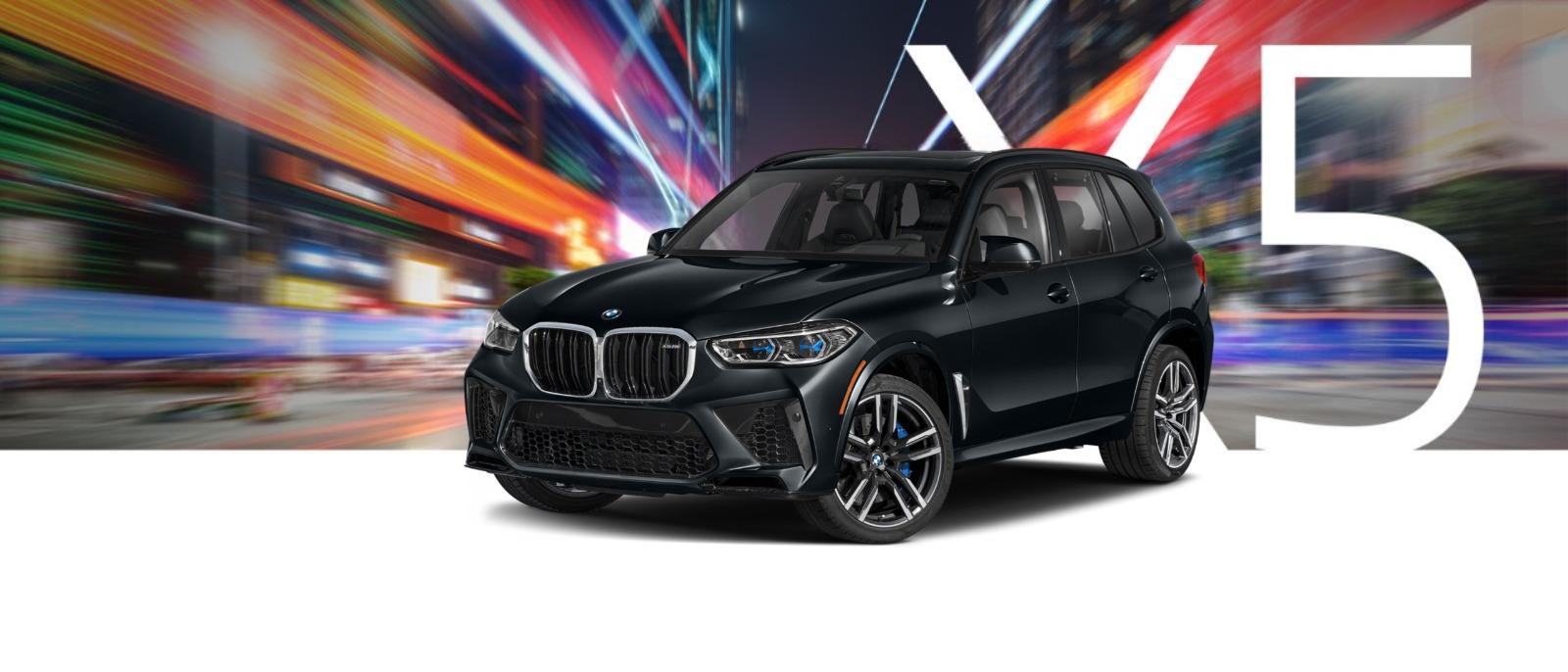 A black BMW X5 on a city street at night with streaks of light.