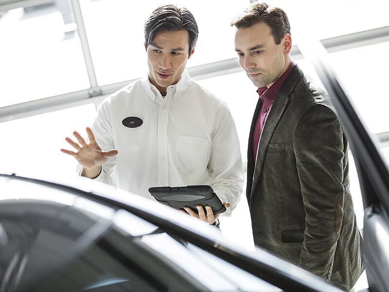 A Salesman talks to a customer about a new car in the showroom.