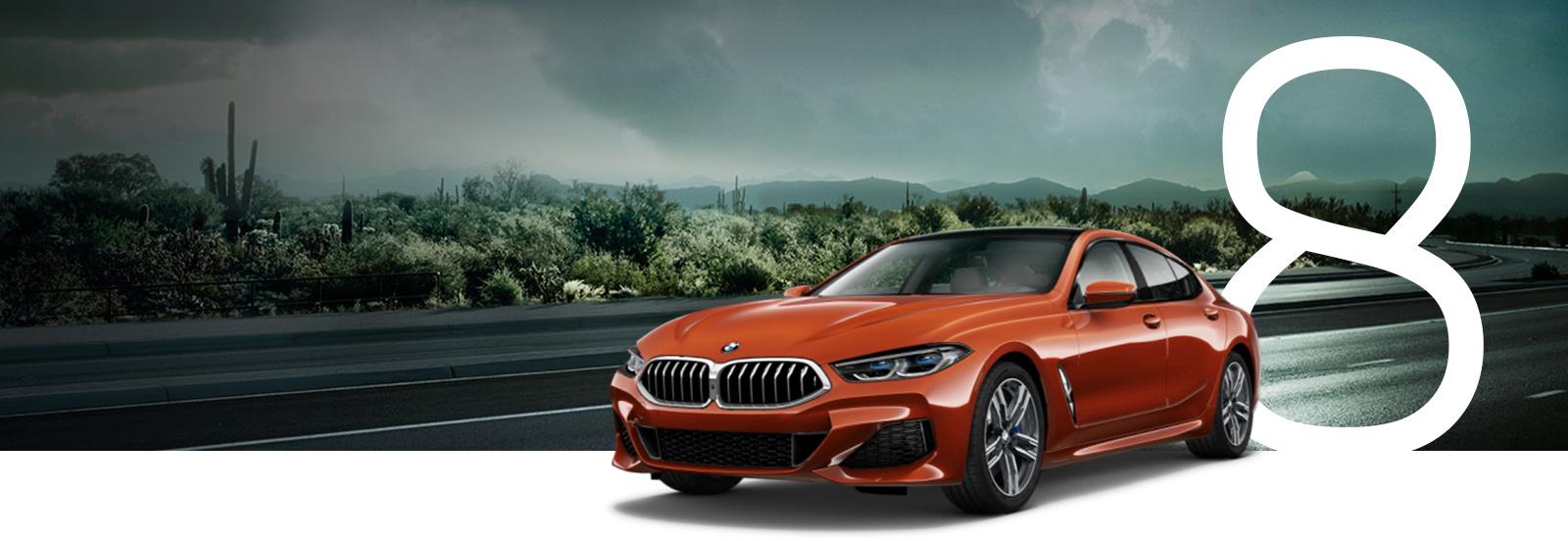 An orange BMW 8 Series driving on a stormy desert road.