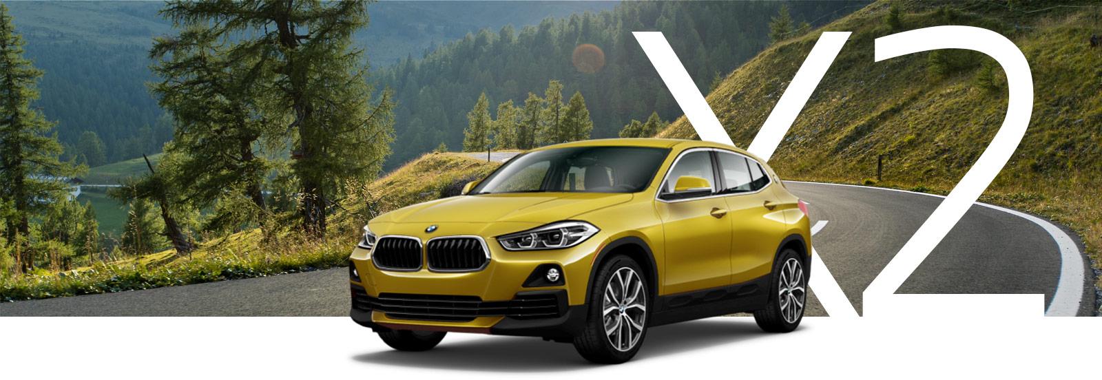 A gold BMW X2 on a curvy mountain road.