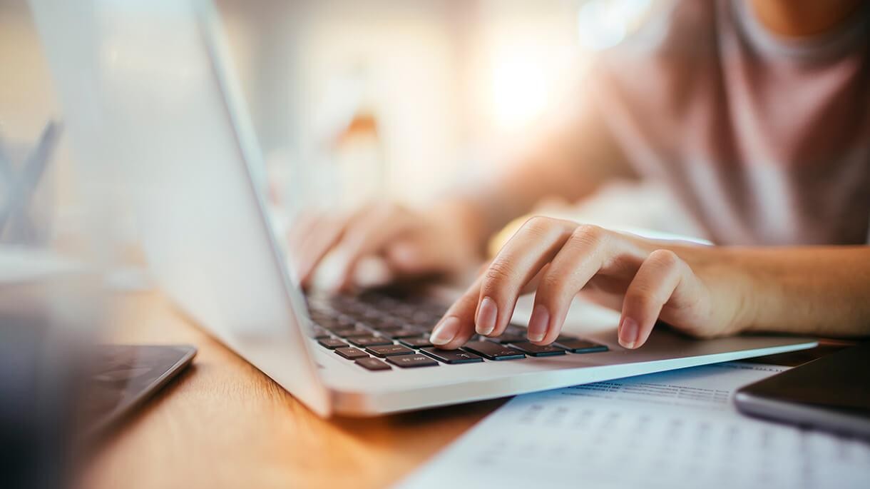 Woman typing on a laptop.