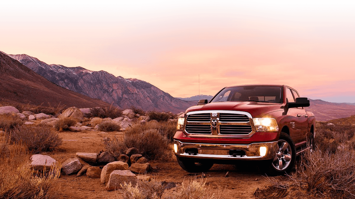 A red RAM 1500 Big Horn truck parked in the high desert at sunset.