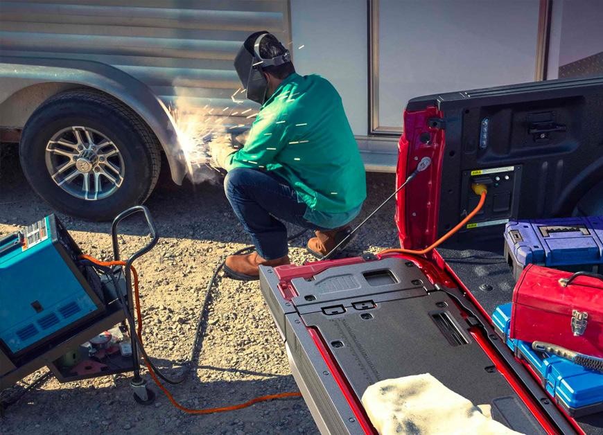 Person using a TIG welder that's plugged into the Pro Power Onboard feature located in the truck bed