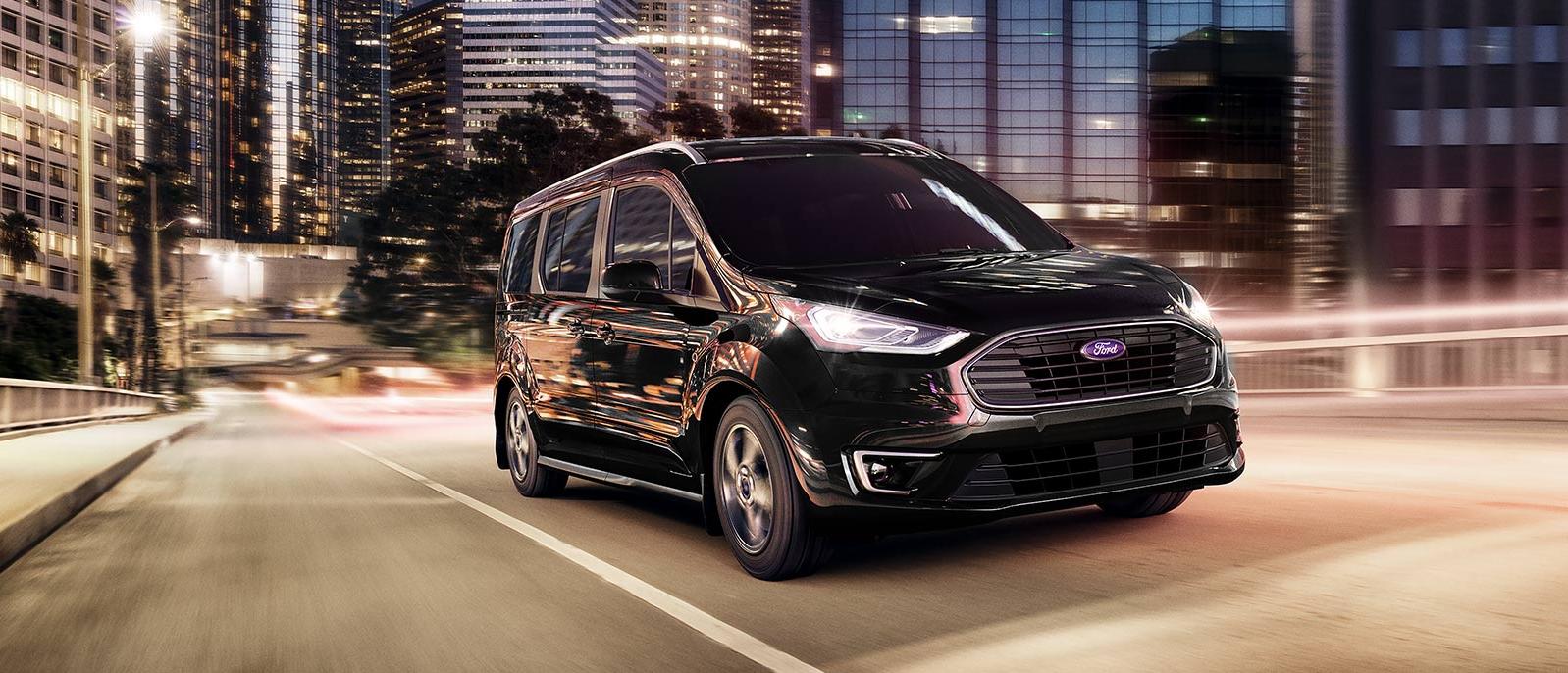 2022 black Ford Transit Connect Van is running on the road at night time.