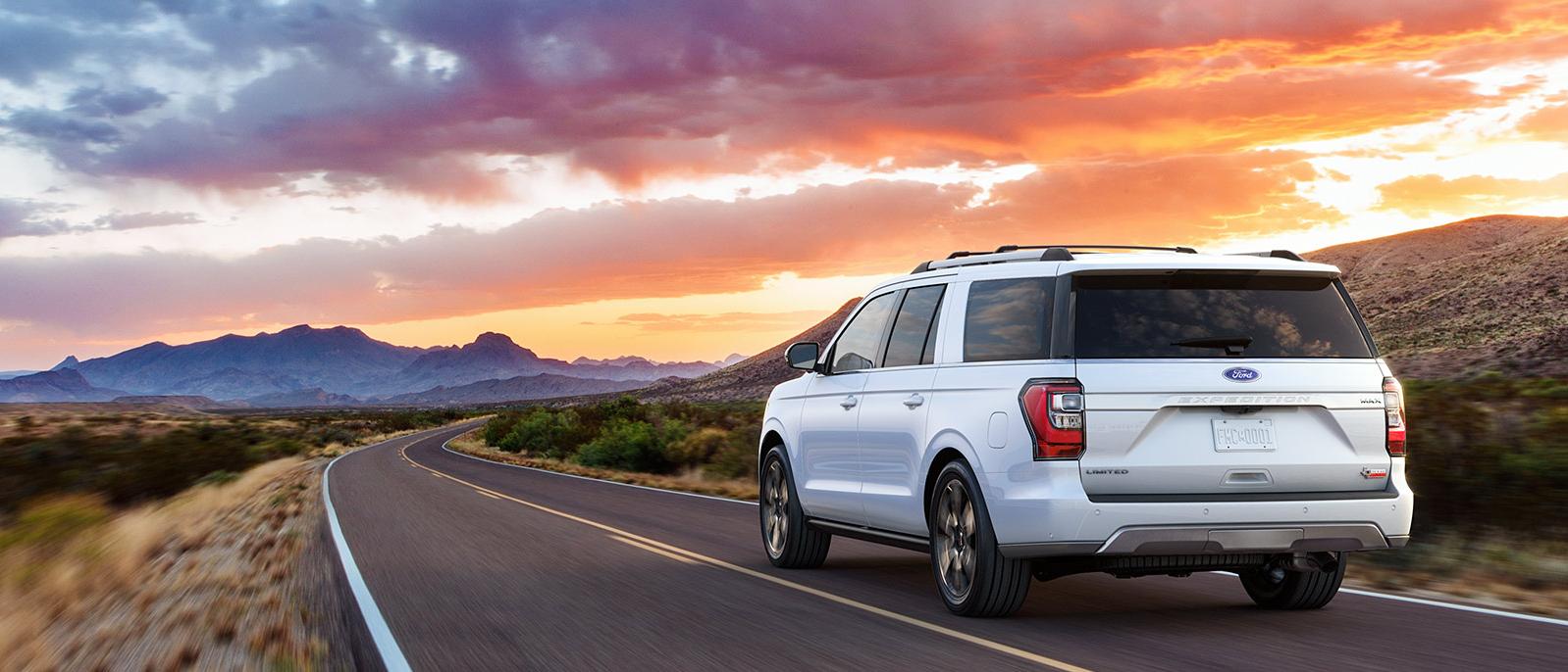 A white Ford Expedition driving into the sunset.