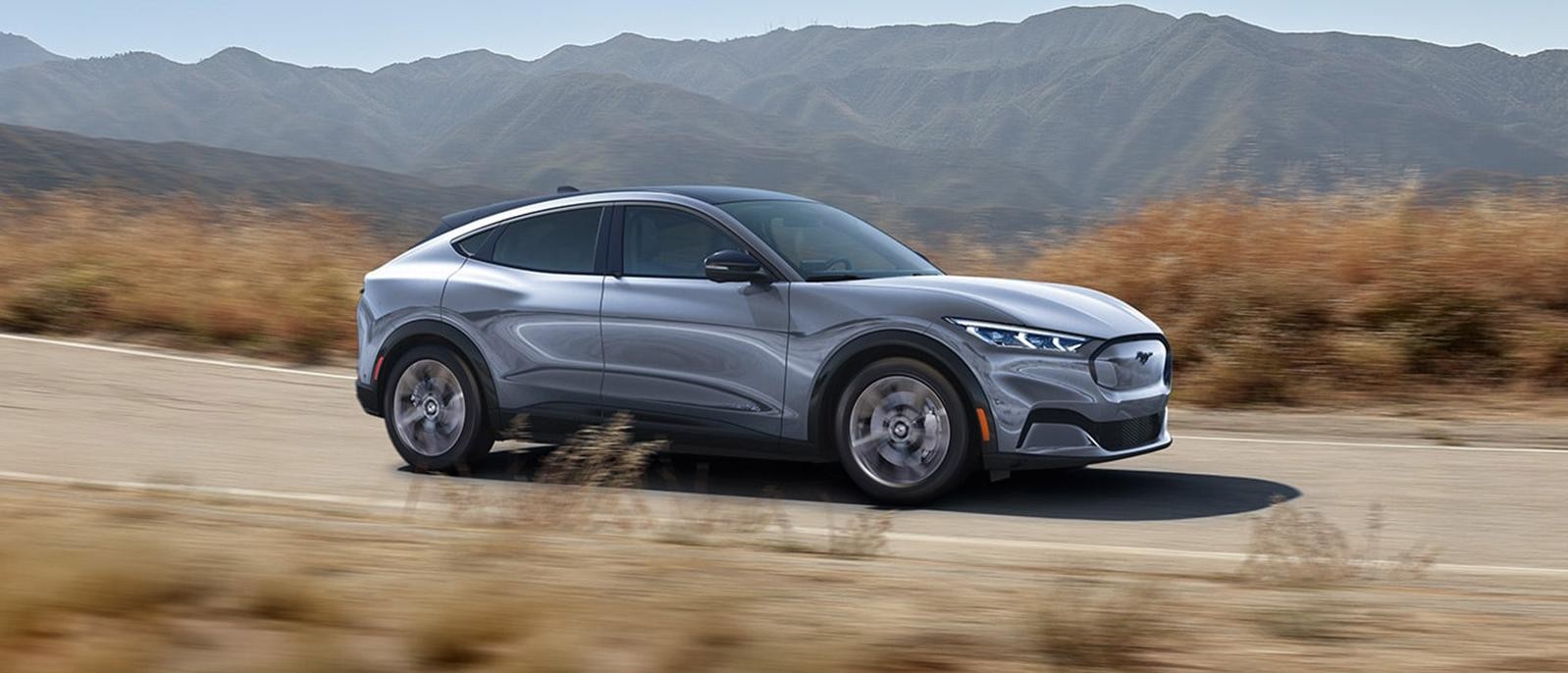 A Silver 2022 Ford Mustang Mach-E is sprinting on the road.