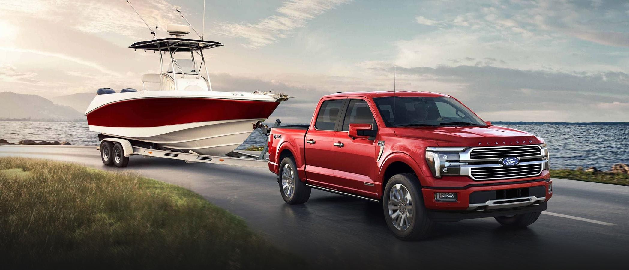 2024 Ford F-150® Platinum Plus pickup in Rapid Red pulling a boat near a lake