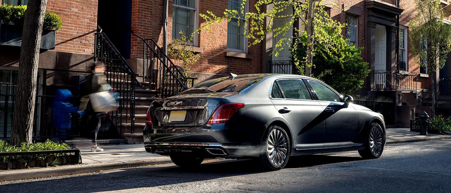 Dark Grey Genesis vehicle driving through urban neighborhood