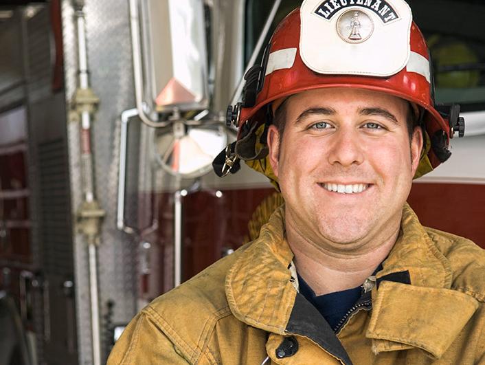 Fireman with a red hat in a firestation smiling