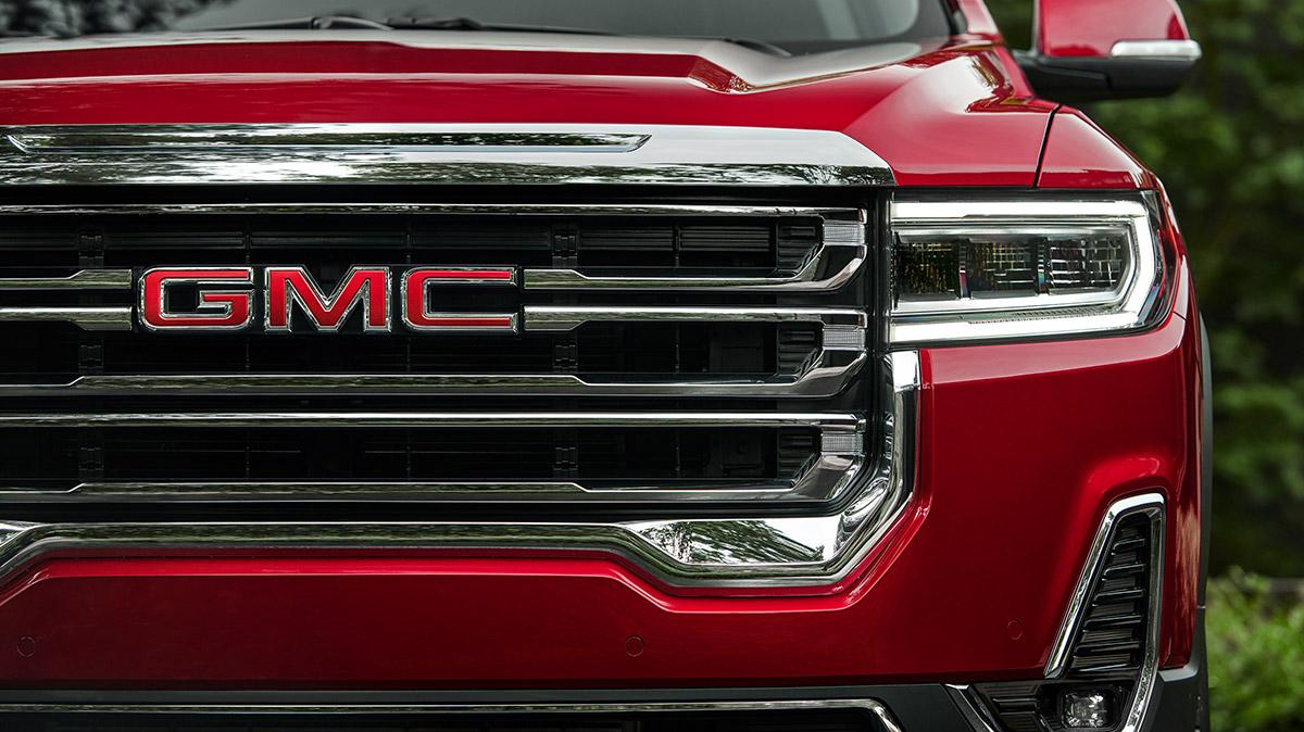 Front grille of a red GMC Acadia featuring the GMC Logo.