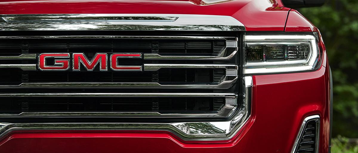 Front grille of a red GMC Acadia featuring the GMC Logo.