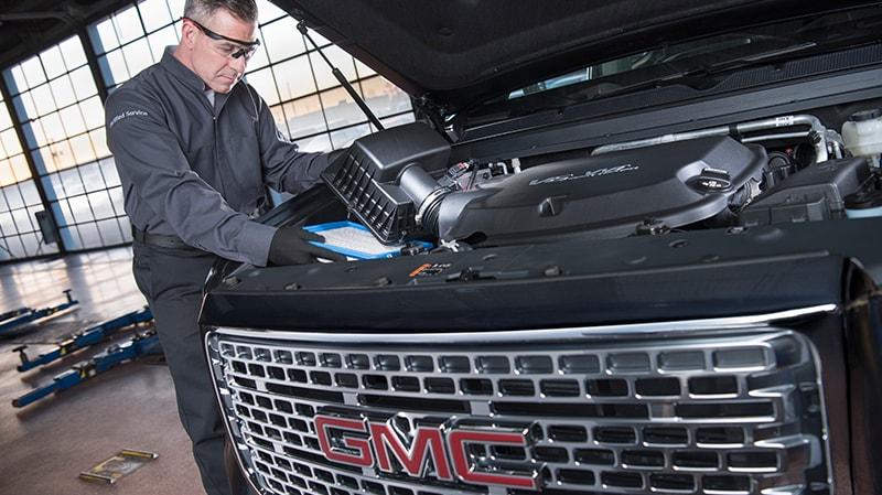 GMC certified service mechanic replacing a vehicle's air filter