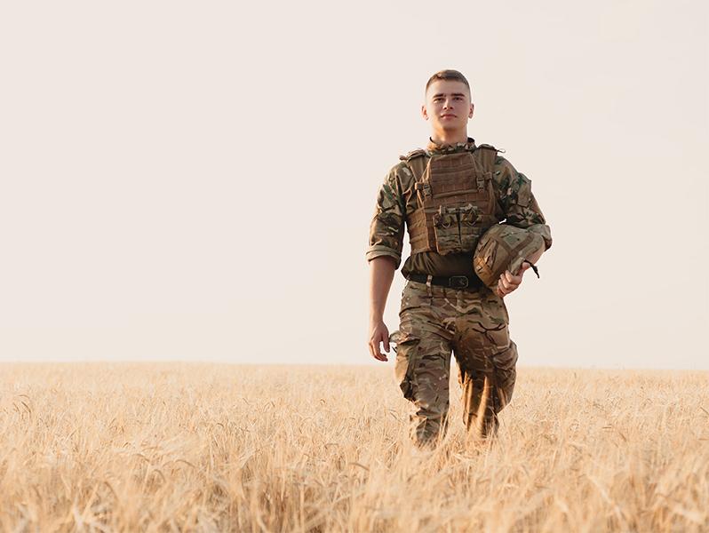 Soldier standing against field 