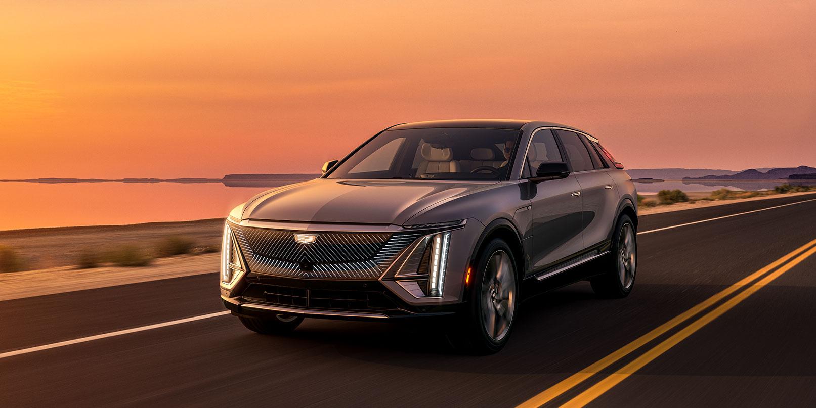 2023 Cadillac Lyriq 3/4 view driving down road in sunset. 