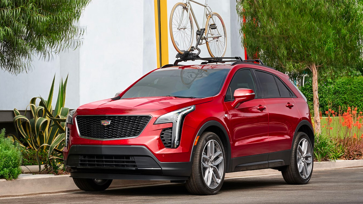 A red Cadillac XT4 parked in a driveway with a bike on the roof rack.