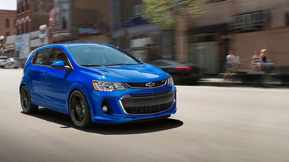Exterior front 3/4 view of the 2019 Chevy Sonic zooming down a city street.