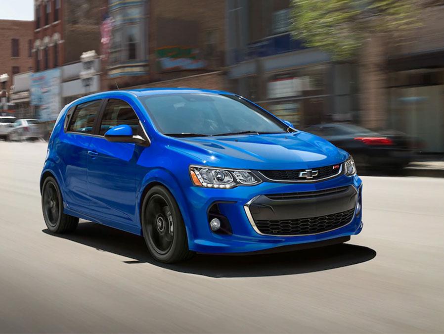 Exterior front 3/4 view of the 2019 Chevy Sonic zooming down a city street.