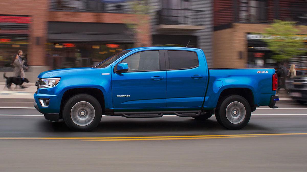 Exterior side-view of 2019 Chevy Colorado truck driving down a city street.