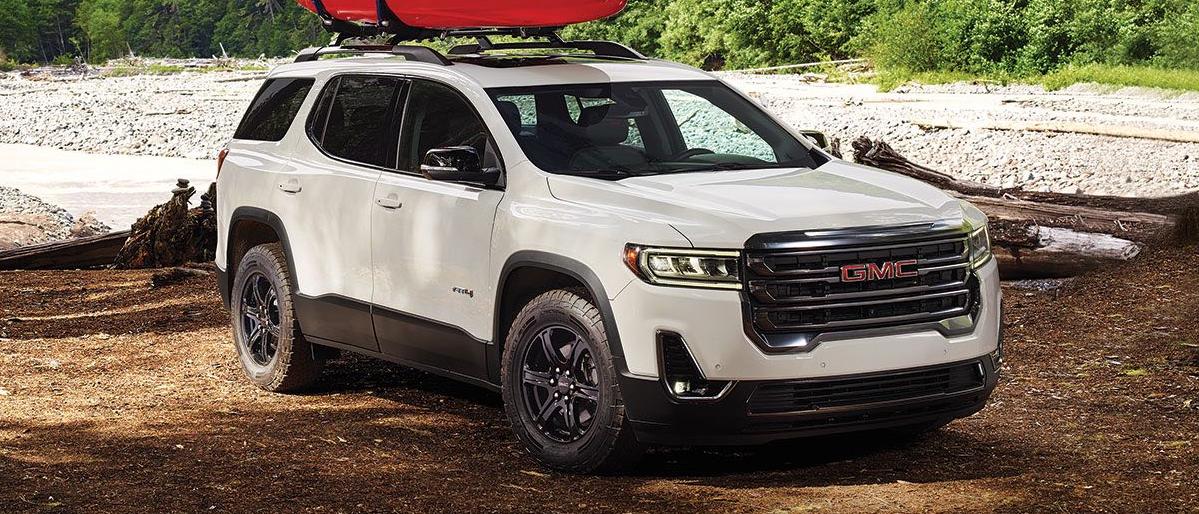2020 GMC Acadia parked in a forest with lake in the background