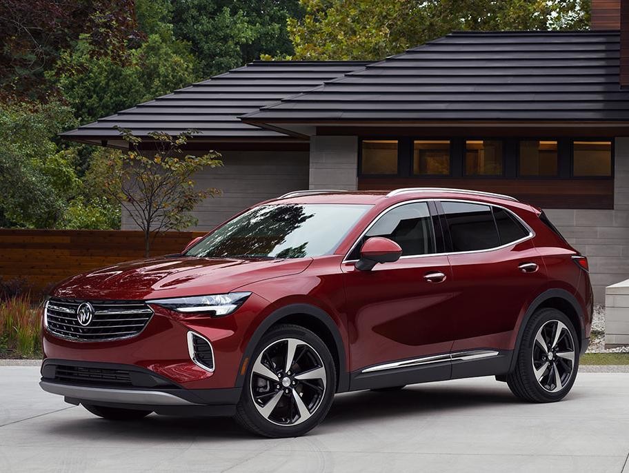 A red Buick Envision parked in the driveway of a modern home with a couple approaching.