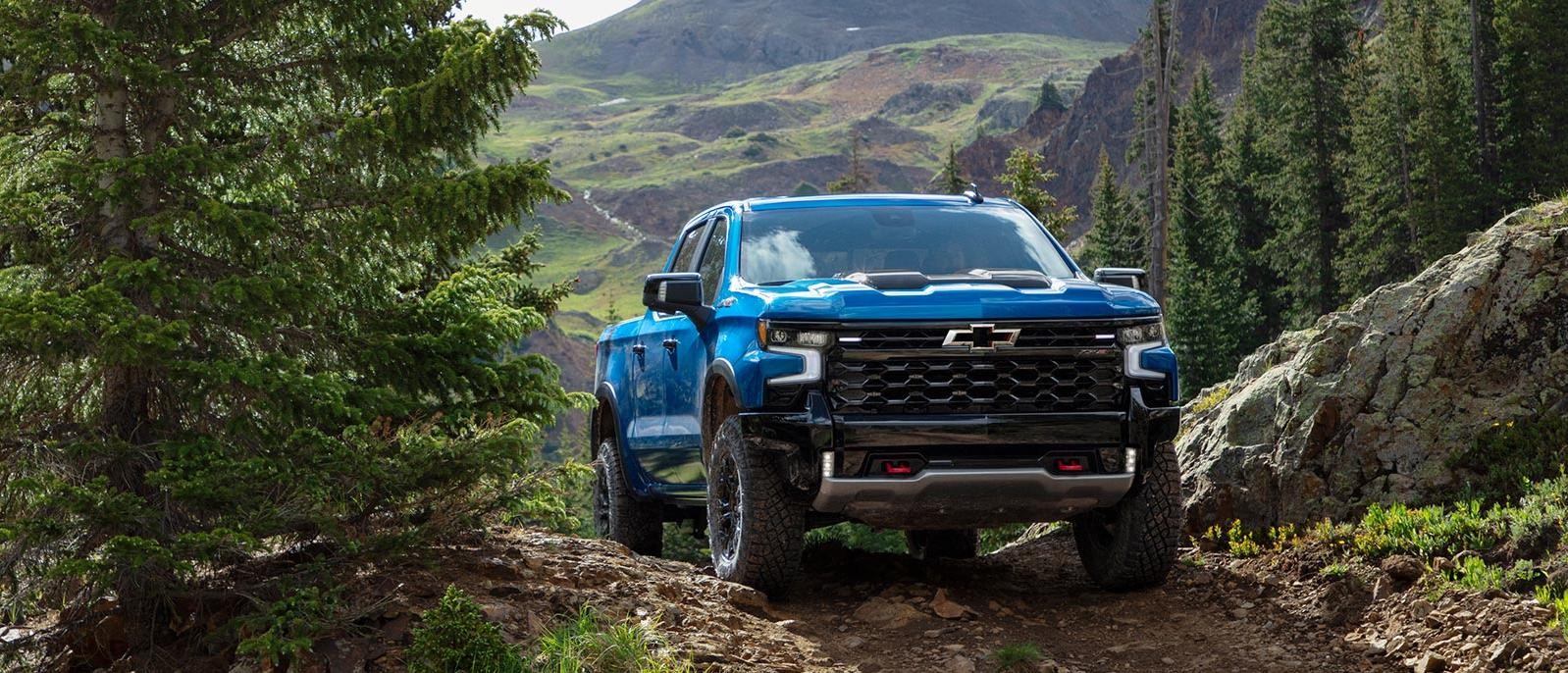 A blue Chevy Silverado 1500 driving through a mountain path.