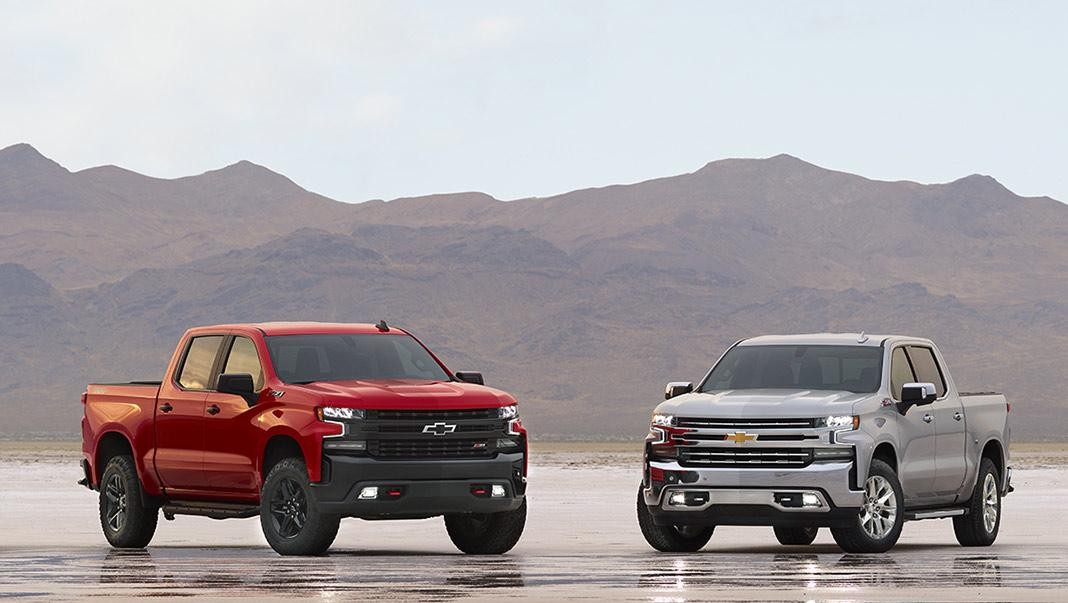 Three Silverado 1500 models on a wet salt-flat in the desert at dusk.