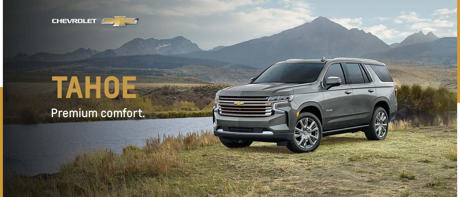 Grey Chevy Tahoe parked in nature with mountains in background 
