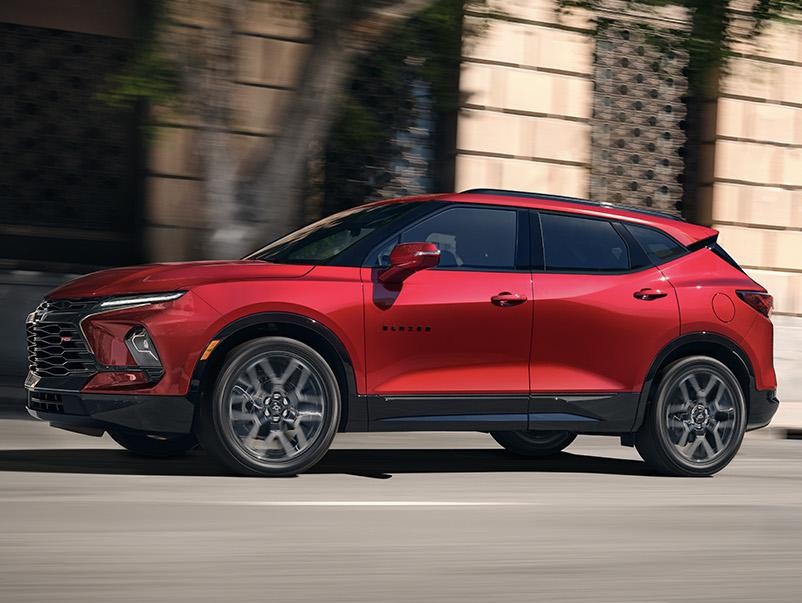 Red Chevy Blazer riding across road in daylight 