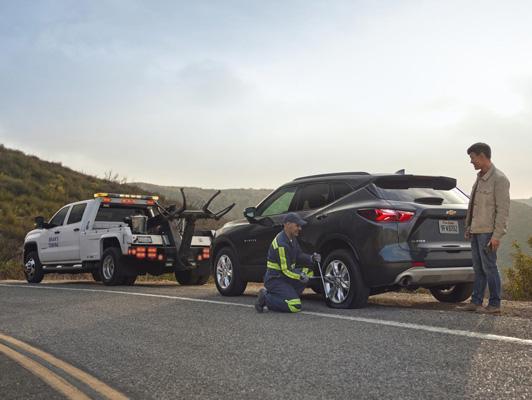 Truck and Equinox on road surrounded with mountains, And worker helping to tow car