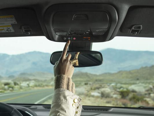 woman pushing onstar button on rear view mirror in desert