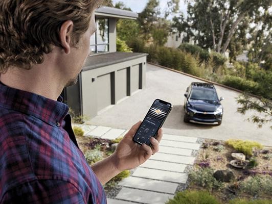 Man holding phone with myChevrolet App and Chevy in background