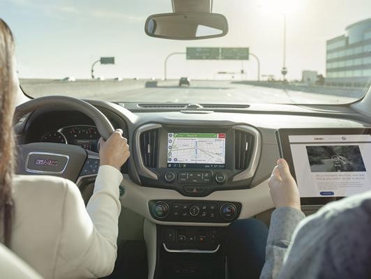 Woman driving using on screen navigation and man on tablet in passenger seat