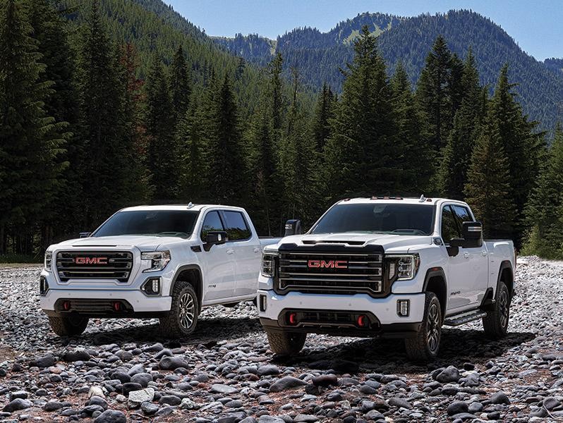 A white GMC Sierra 1500 and 2500HD parked on a riverbed.