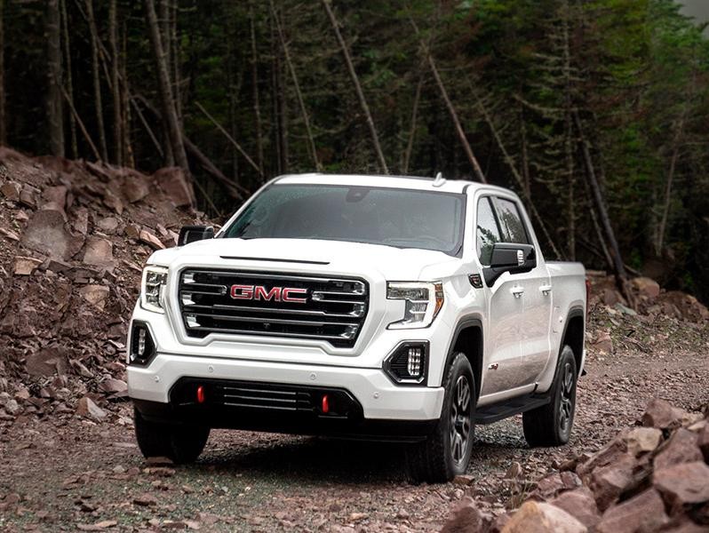 A white GMC Sierra 1500 Crew Cab on a mountain road.