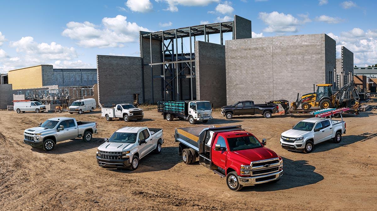 Lineup of Chevy work vans at a building construction site.