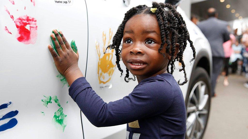 Young girl adding a paint hand print to hyundai vehicle