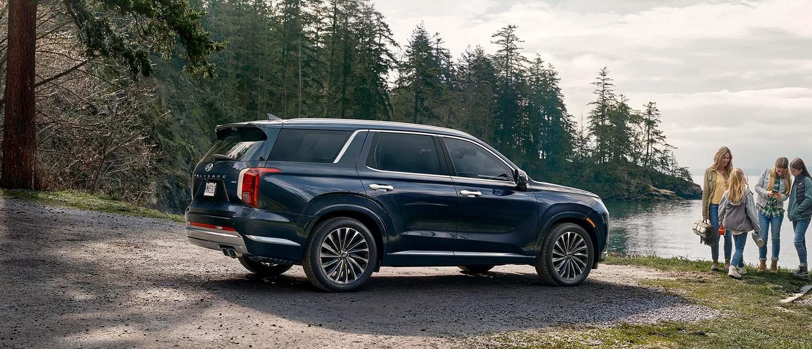 A dark grey Hyundai Palisade parked next to a waterbody.