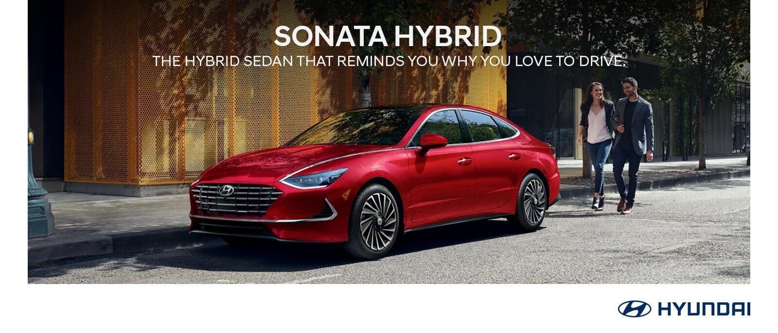 2023 Red Hyundai Sonata Hybrid with tree and building in background.