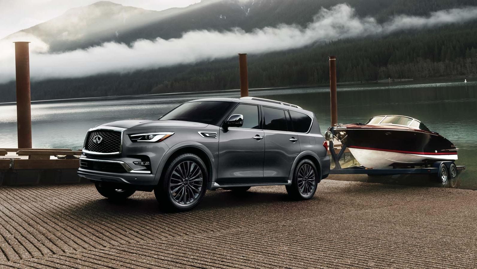 Gray 2023 QX80 towing a boat on a launch