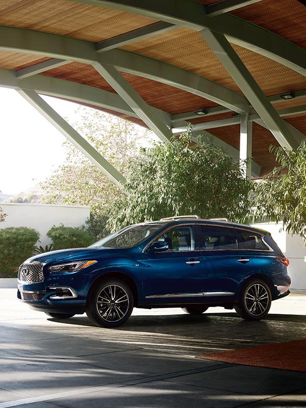 Profile view of a blue INFINITI QX60 parked under an archway.