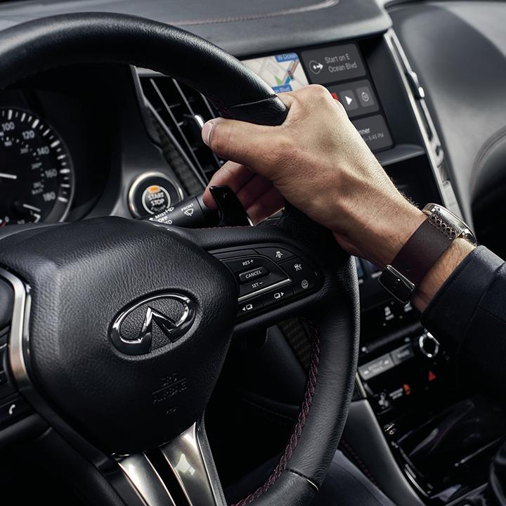 Close-up view of driver using the paddle shifter of an INFINITI Q50.