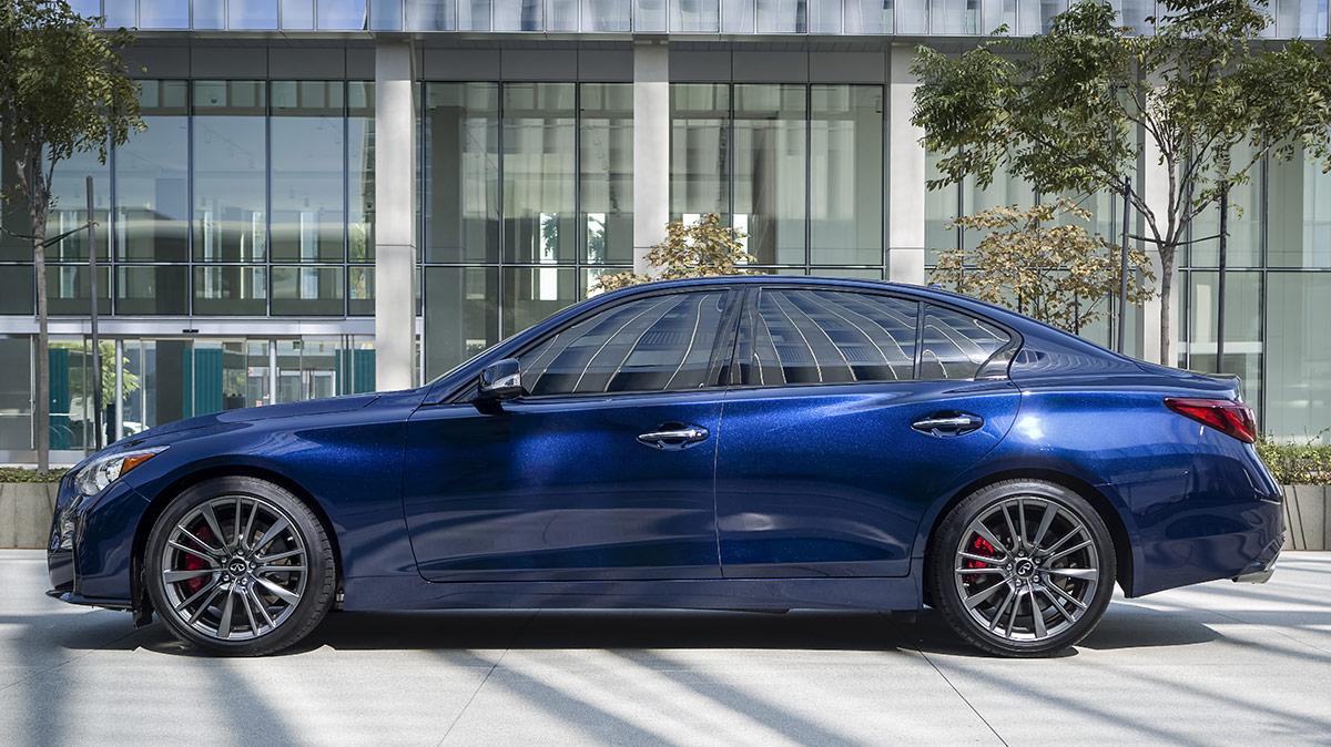 Profile view of a blue INFINITI Q50 parked in front of a building in the city.