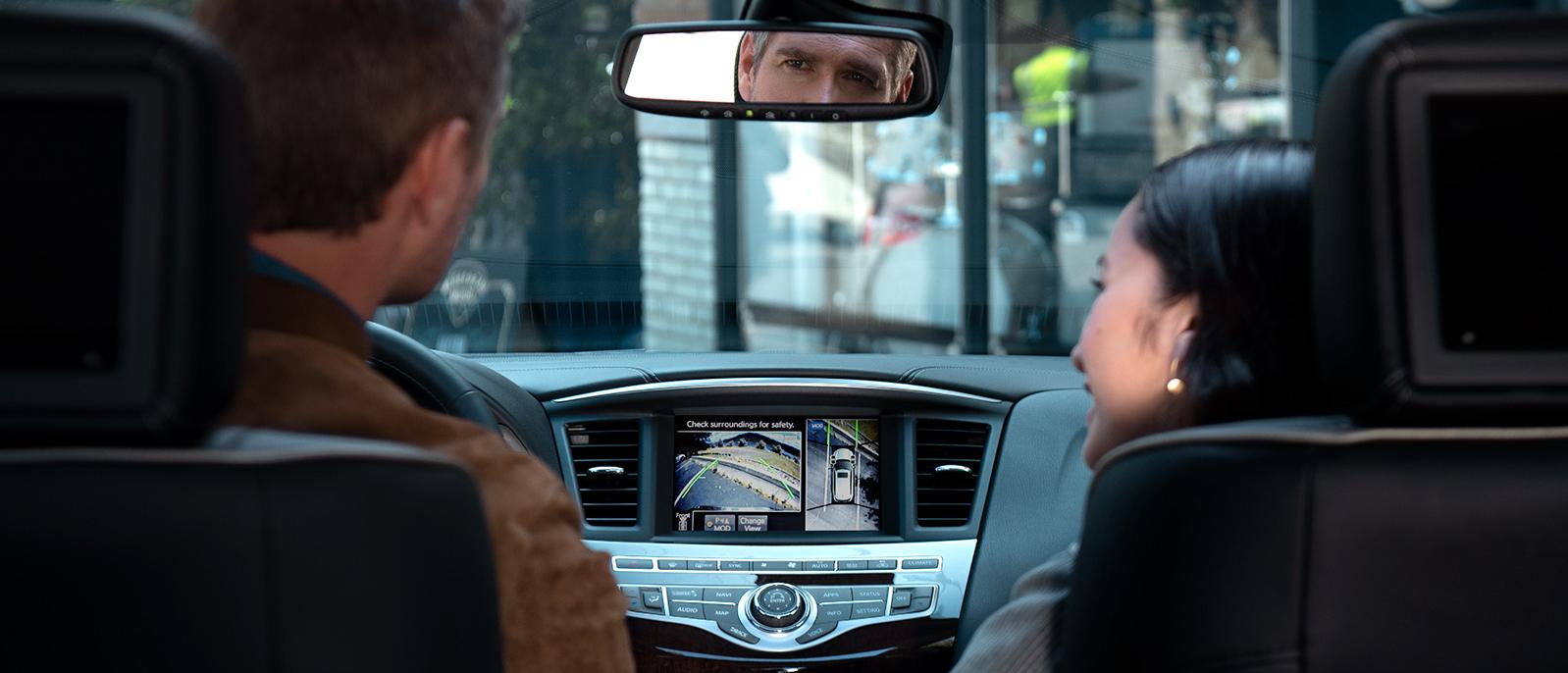 A couple in their INFINITI QX60 with the Around View feature engaged on the touchscreen.