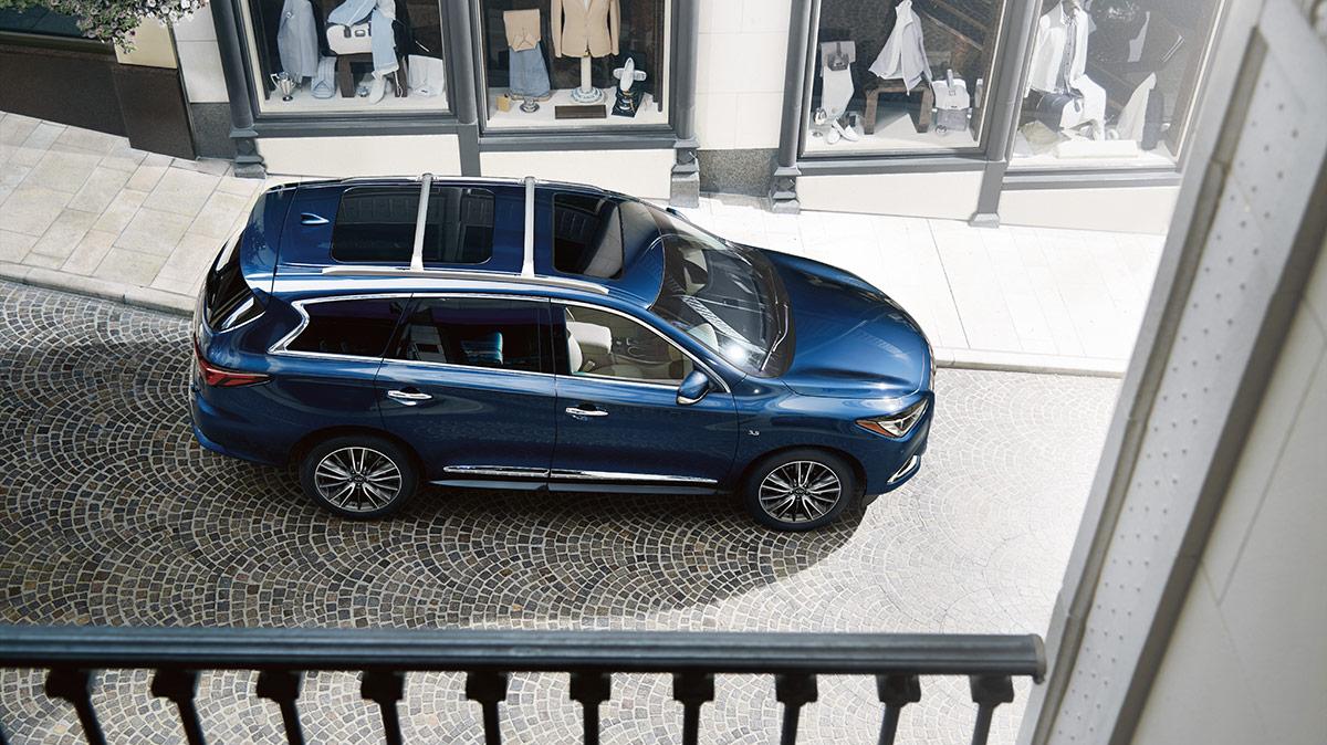 High angle view of a blue INFINITI QX60 on the street below a balcony.