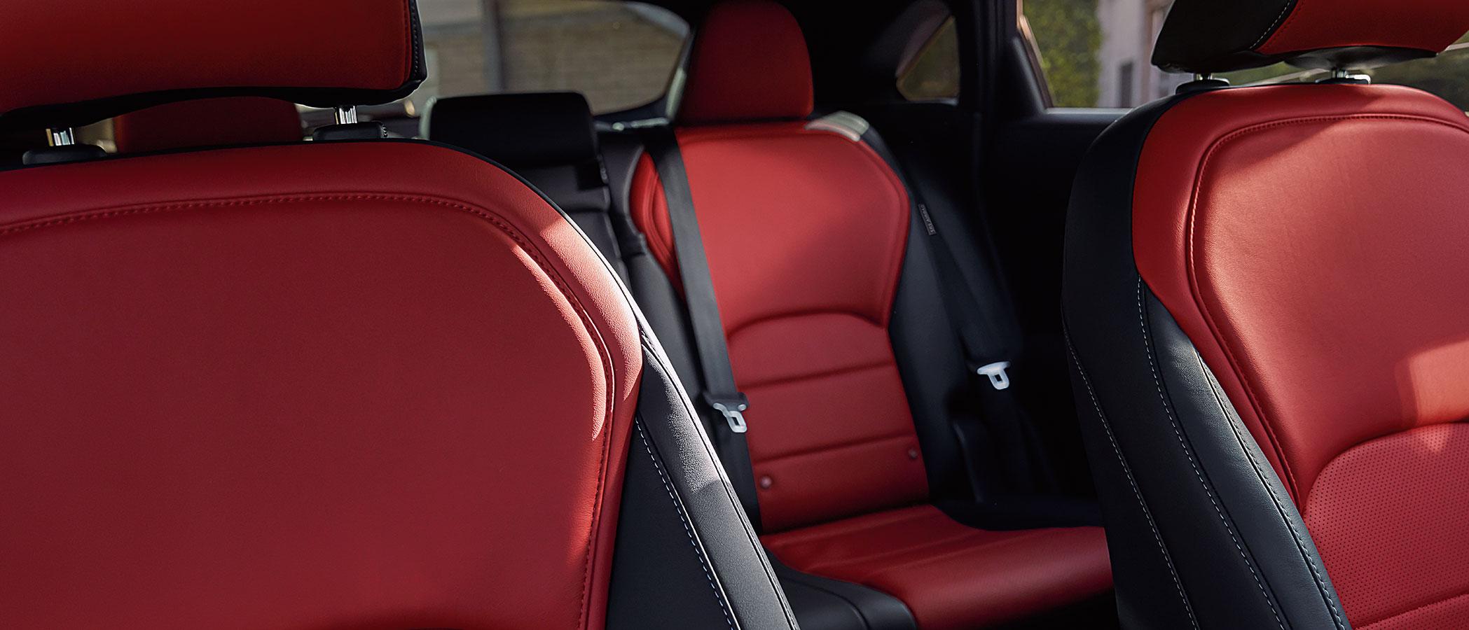 Interior view of the INFINITI QX55 featuring black upholstery with Monaco red accents.